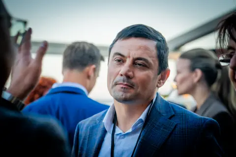 Attendee in a navy blazer listening in the rooftop crowd