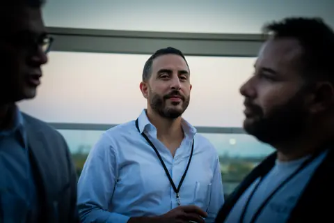 Attendee with an event lanyard listening during a conversation