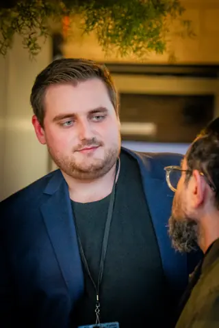 Attendee in a navy blazer under the warm lights by the bar