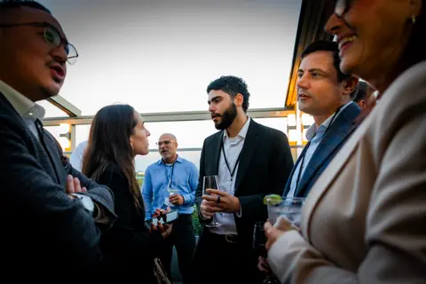Group of attendees talking on the rooftop as the sun goes down