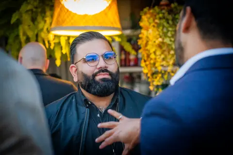 Attendee in glasses talking under the woven pendant lights