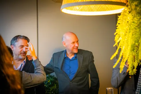 Two attendees laughing under a woven pendant light at the ElevateOS Montreal event