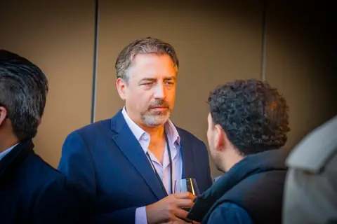 Attendee in a navy blazer listening to another guest