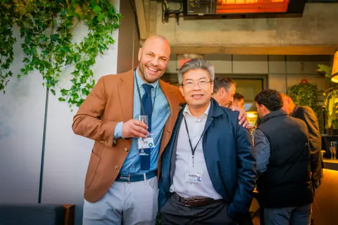 Two attendees posing together by the ivy wall