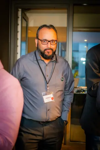 Attendee in glasses with an event badge standing by the terrace doors