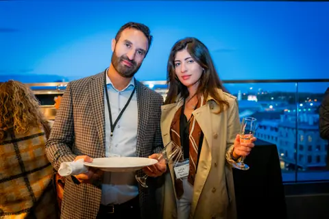 Two attendees posing on the rooftop at blue hour with Montreal's lights behind them