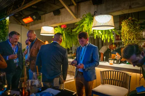Attendees in conversation under the pendant lights as the evening continues