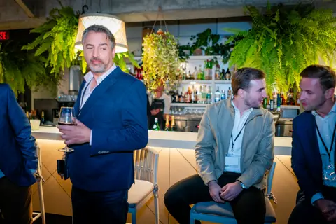 Attendees gathered around the bar under hanging ferns and pendant lights