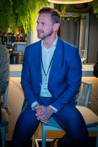 Panelist in a blue suit seated by the bar before the panel discussion