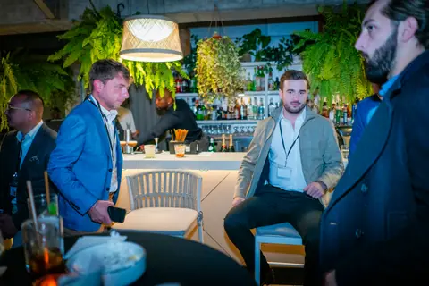Panelists taking their seats on stools by the rooftop bar
