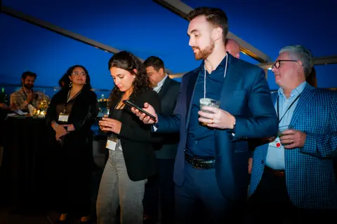 Attendees standing and listening to the panel on the terrace at night