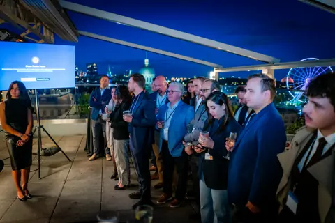 Audience standing to watch the panel with the Old Port lit up at night behind them