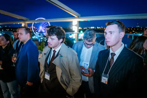 Attendees listening to the panel with the Old Port Ferris wheel lit up behind them