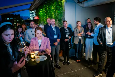 Seated and standing attendees following the panel discussion on the terrace