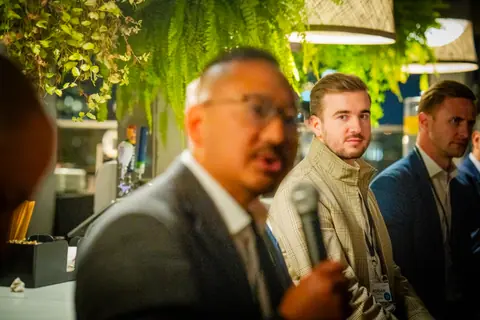 Panelist speaking into a microphone as other panelists listen