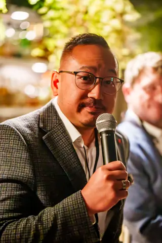 Panelist in a tweed blazer speaking to the audience