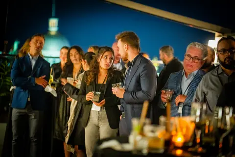 Attendees listening around a candlelit table on the rooftop