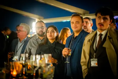 Group of attendees with drinks listening to the panel