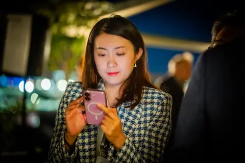 Attendee checking her phone during the evening on the terrace