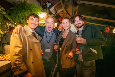 Group of five attendees posing together and laughing on the rooftop