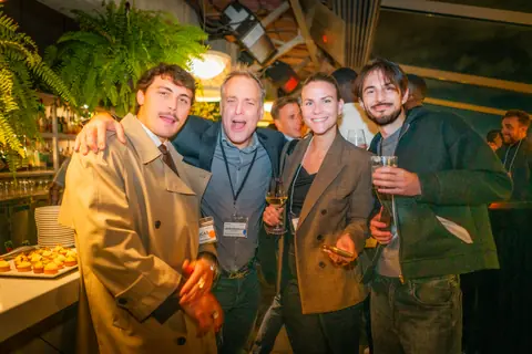 Five attendees posing arm in arm late in the evening