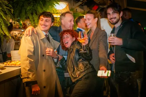 Attendees laughing and posing together by the bar late in the evening