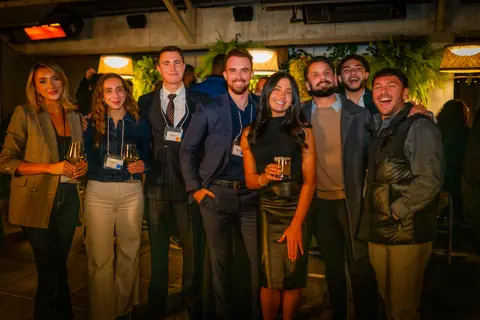 Large group of attendees with event lanyards posing together on the rooftop