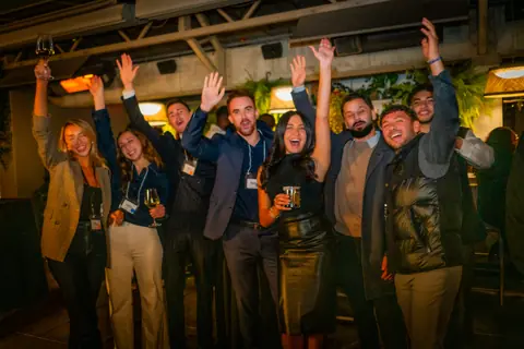 Group of attendees cheering with their arms raised for the camera