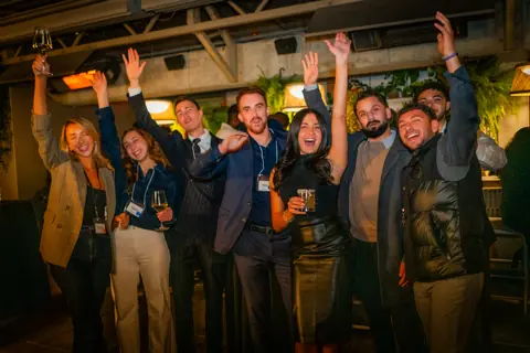 Attendees celebrating with raised arms in a group photo on the rooftop