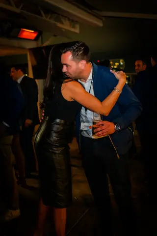 Two attendees hugging on the rooftop at night