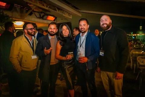 Group of attendees with event badges posing together after dark