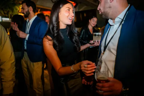 Two attendees laughing in conversation at night