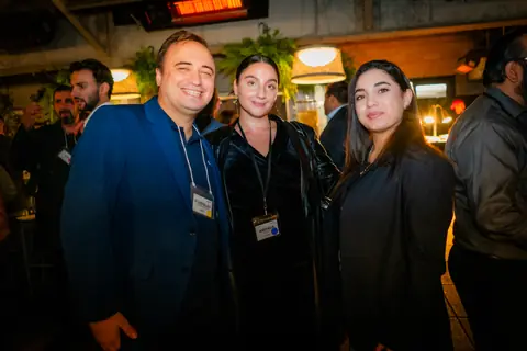 Three attendees posing together under the terrace heaters