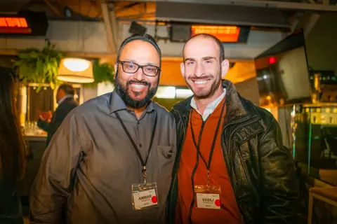 Two attendees with event badges smiling side by side