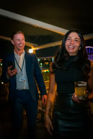 Two attendees with drinks on the terrace at night
