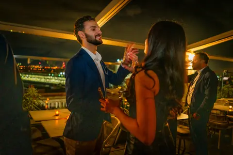 Two attendees toasting on the rooftop at night