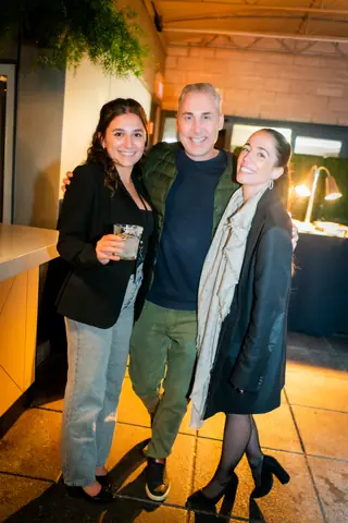 Three attendees posing together by the bar at night