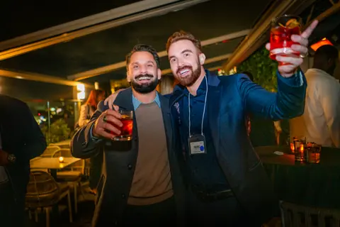 Two attendees raising red cocktails in a toast