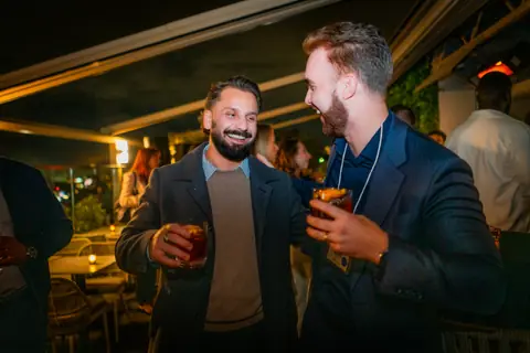 Two attendees laughing together with cocktails