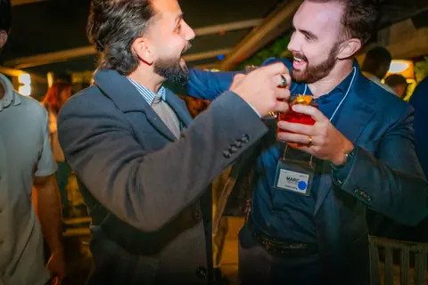 Attendee adjusting a friend's event badge with a laugh