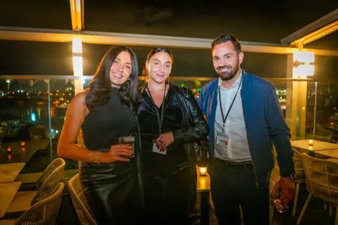 Three attendees posing together with the city lights of Old Montreal behind them