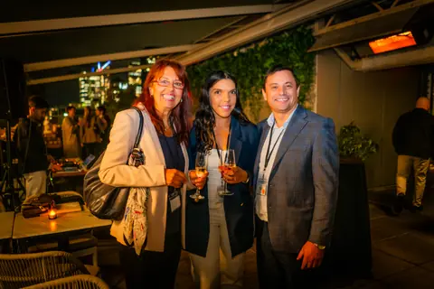 Three attendees posing together with the downtown Montreal skyline lit up behind them