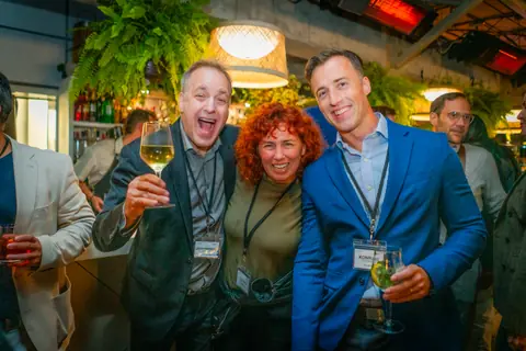 Attendees laughing and raising their glasses under the pendant lights