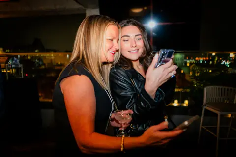 Two attendees looking at photos on a phone together