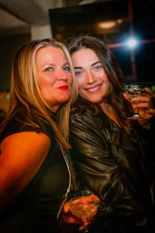 Two attendees smiling together with drinks at night