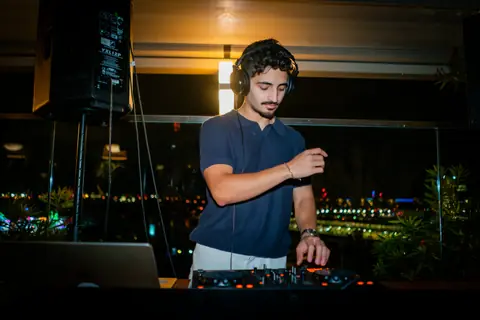DJ playing music for guests on the rooftop at night