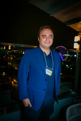 Attendee in a blue blazer standing on the rooftop at night