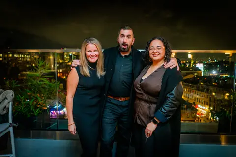 Three attendees posing together with the city lights behind them