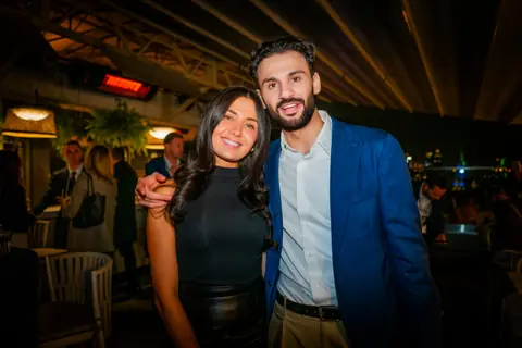 Two attendees posing together under the terrace roof at night