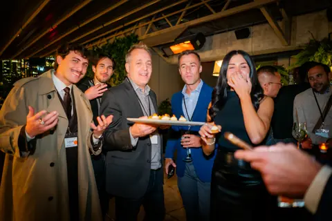Attendees laughing together as canapés are passed around late in the evening